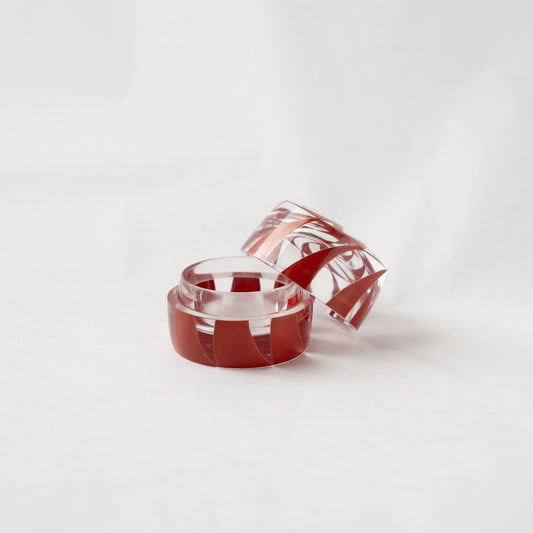 The acrylic Makie small box with its lid slightly removed and resting on the rim, showcasing the internal polished chamber and the optical refraction of the red lines.