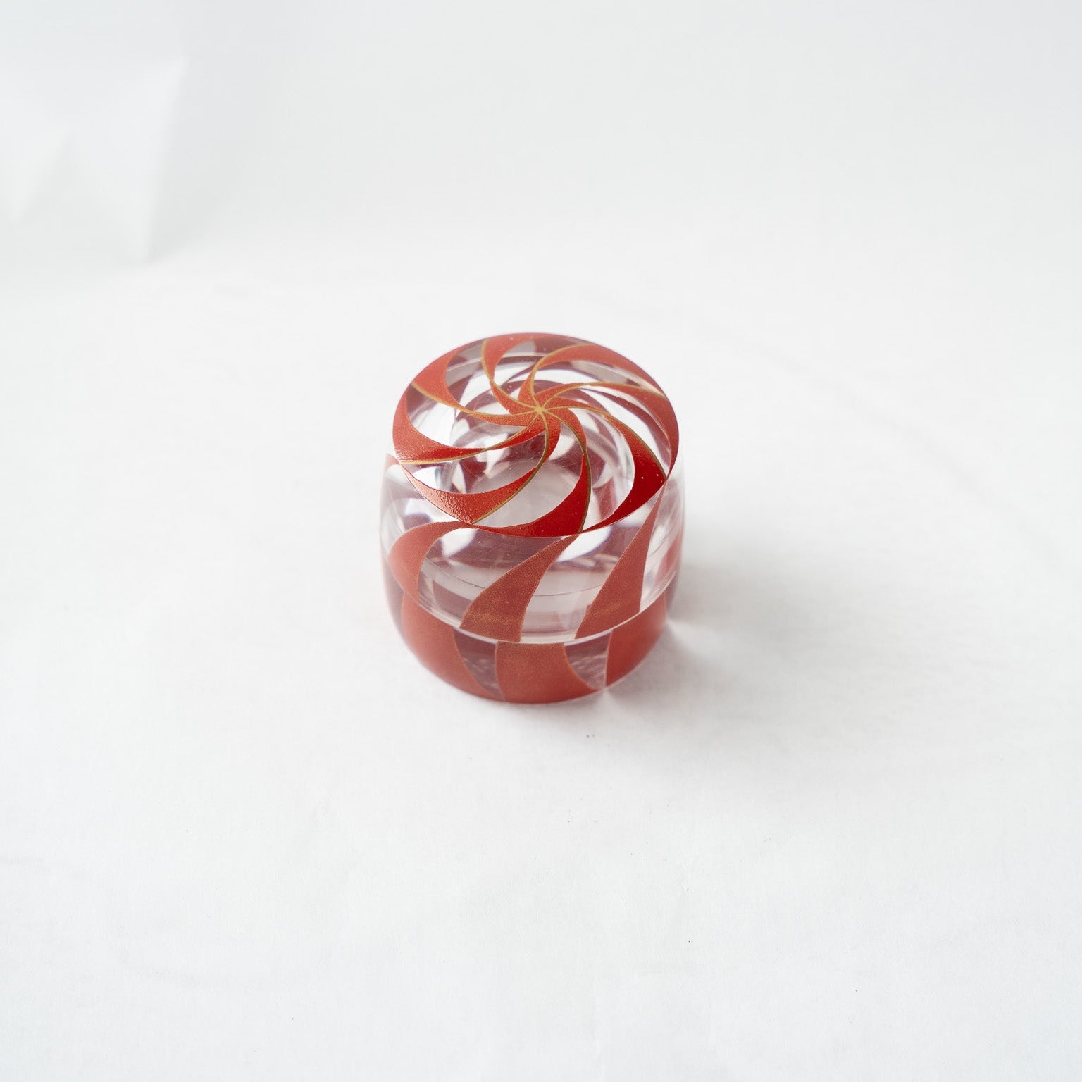 High-angle top view of the #91 spiral acrylic box, highlighting the thick clear walls of the container and the golden shimmer embedded in the red lacquer strokes.