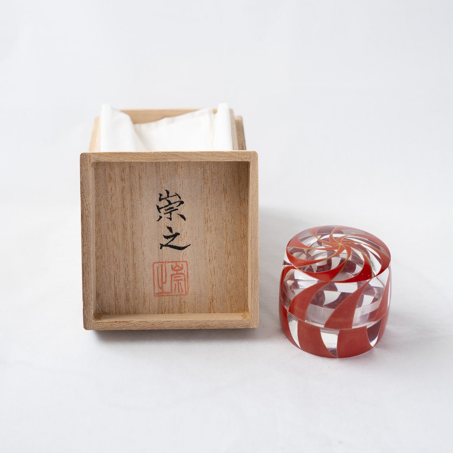 The acrylic spiral small box standing next to its traditional paulownia wooden box (Tomobako), featuring the handwritten calligraphy and red seal stamp of artist Takayuki.