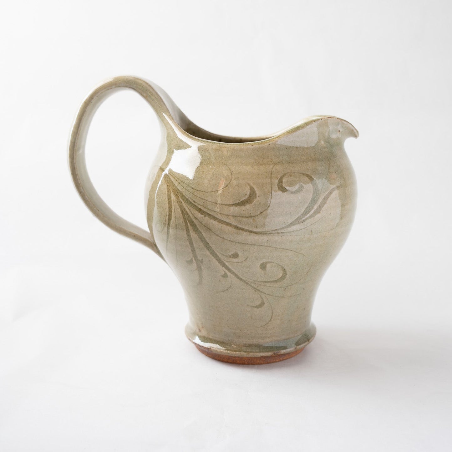 Opposite side profile of the incised ceramic pitcher, emphasizing the elegant junction where the handle meets the rim and the natural gradient of the ash-green glaze.