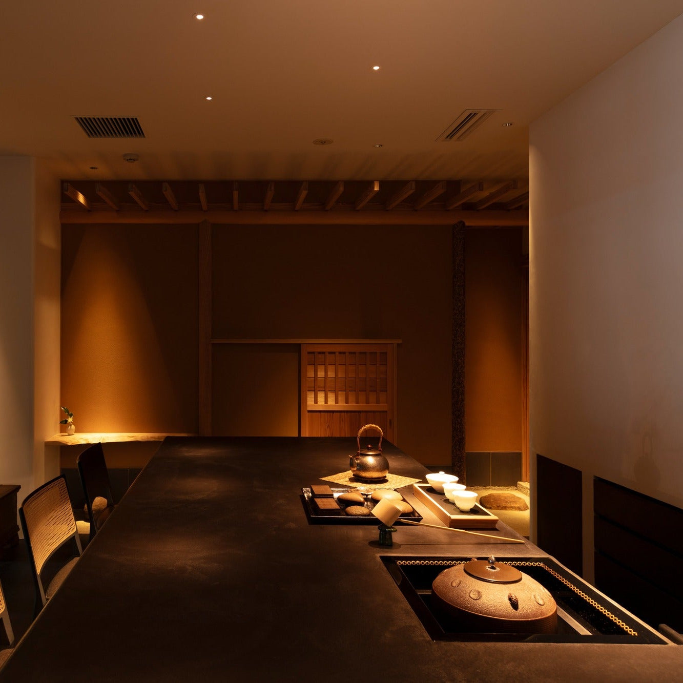 A silver kettle and tea bowls wait on the counter beside a sunken brazier, the heart of the japanese cafe.