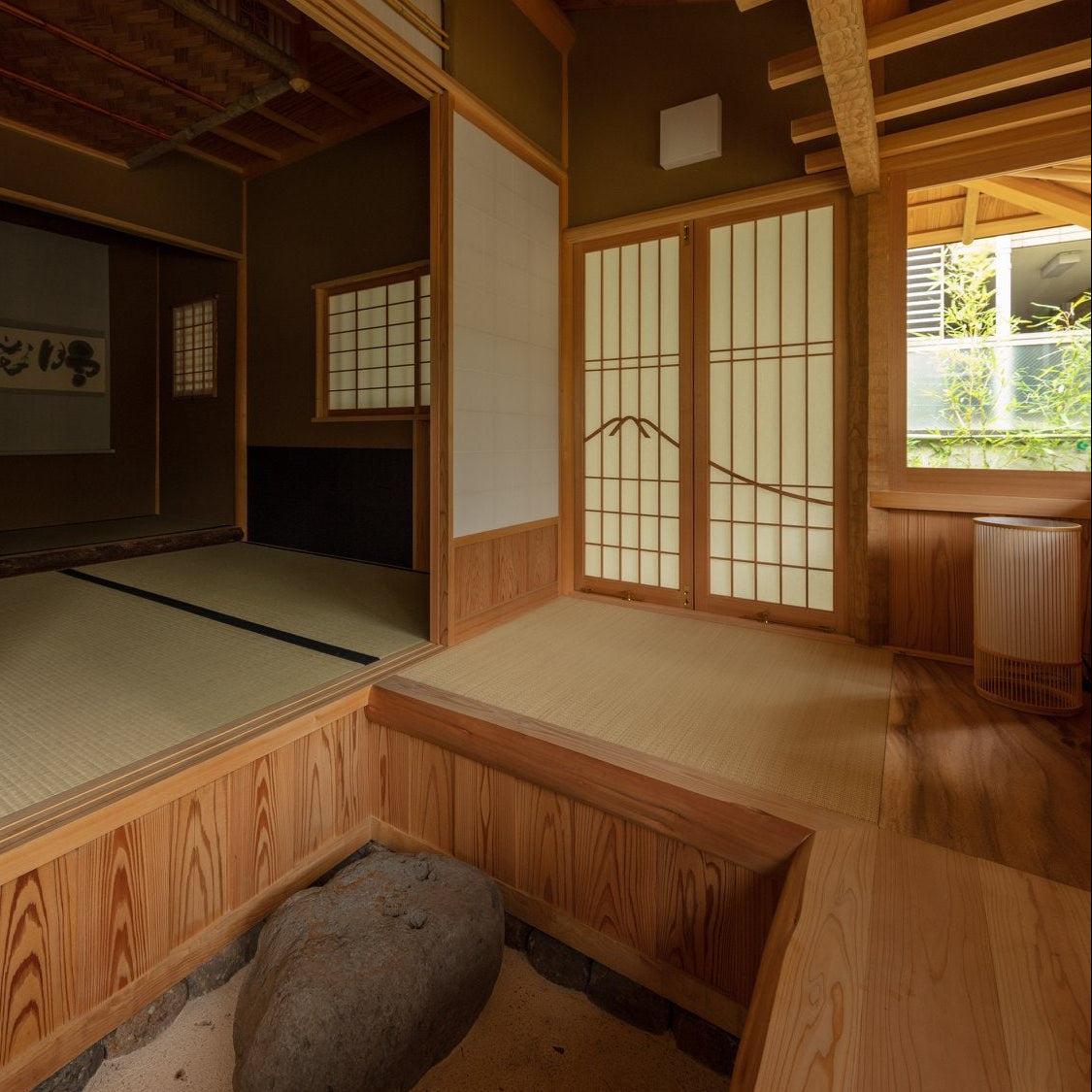 Japanese tea room with an indoor stone-and-sand court, hanging scroll and paper lamp, traditional chashitsu architecture.