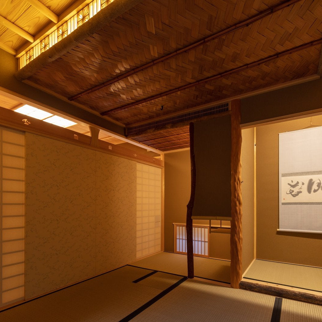 Tatami tea room at night with a tokonoma, calligraphy scroll and kumiko lattice, a traditional Japanese architecture detail.