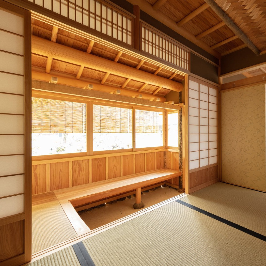Japanese tea room interior with a timber bench, sunken earthen step and tatami flooring, traditional chashitsu architecture.