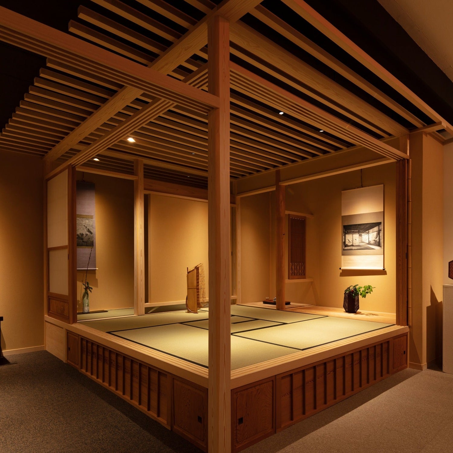 Raised tatami tea room (chashitsu) under a slatted canopy ceiling with hanging scrolls, beneath a Ginza gallery — refined Japanese architecture.