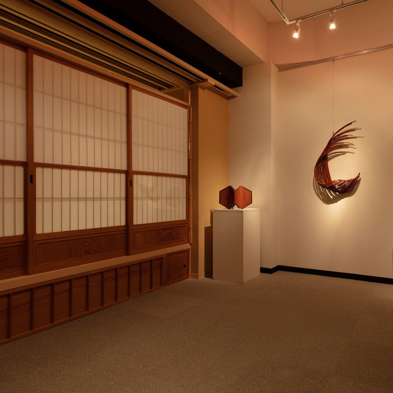 Gallery corner with woven bamboo artworks on pedestals beside a shoji wall, a Japanese interior in Ginza.