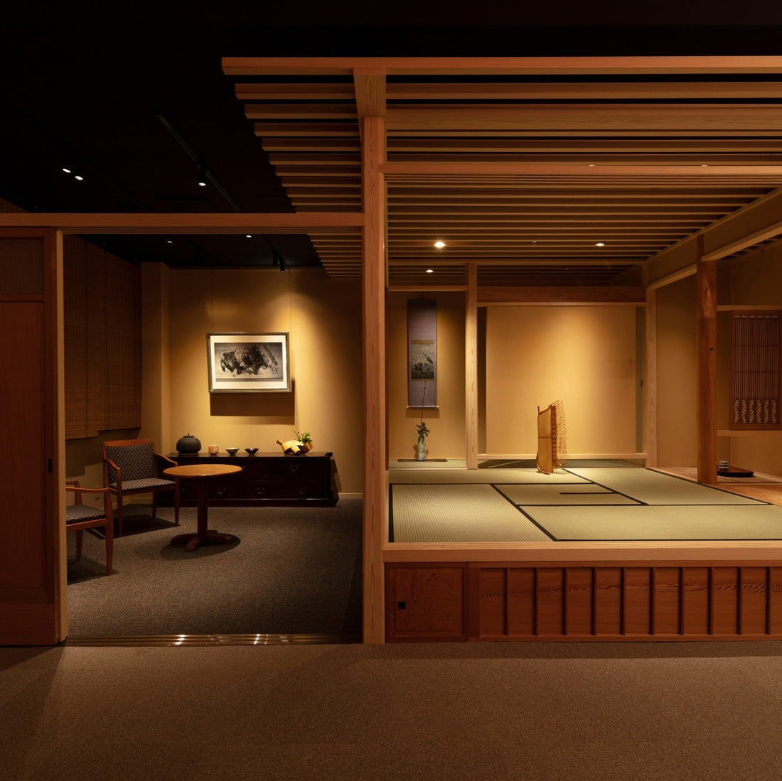 View from the gallery into a raised tatami tea room (chashitsu), with artworks on the surrounding walls.