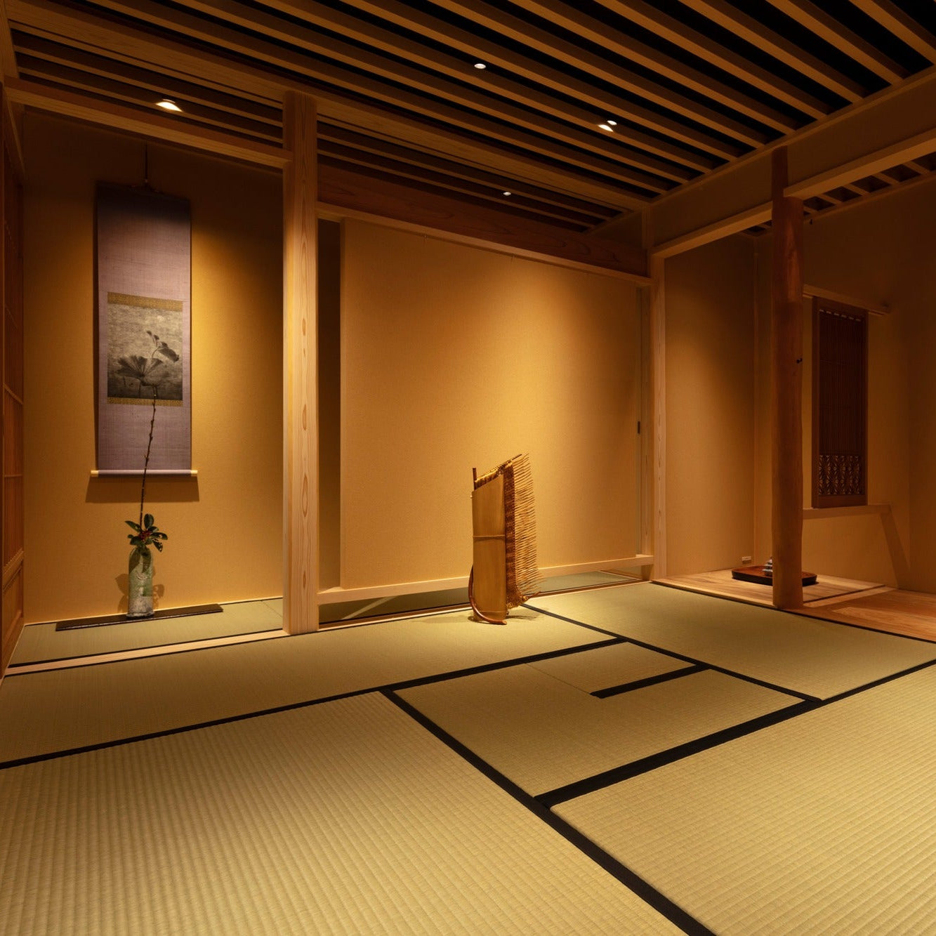 Tatami tea room with hanging scrolls and a bamboo sculpture, lit for evening in a Ginza gallery.
