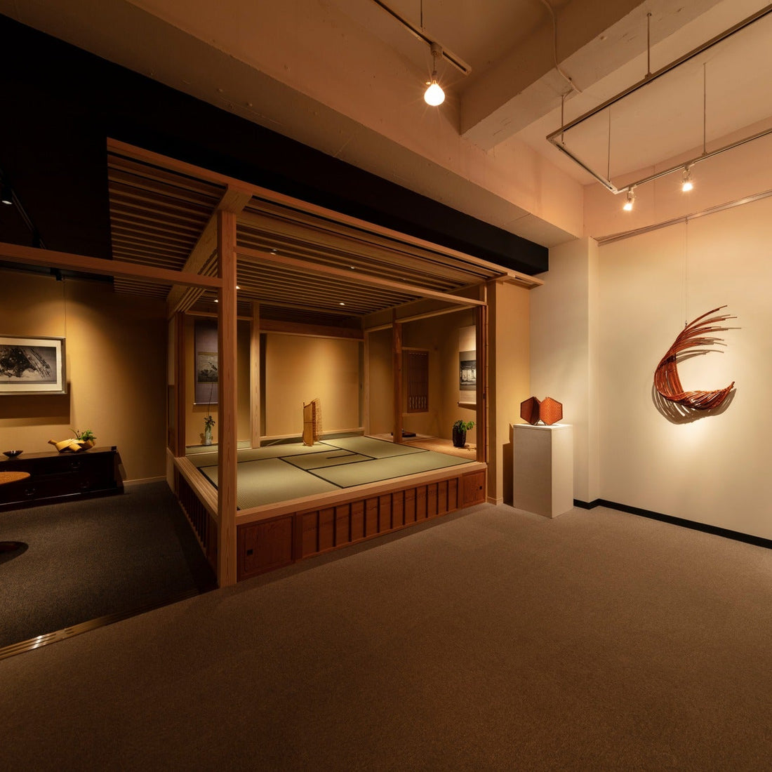 Wide view of a raised tatami chashitsu alongside a gallery of bamboo and ceramic art in Ginza, Tokyo.
