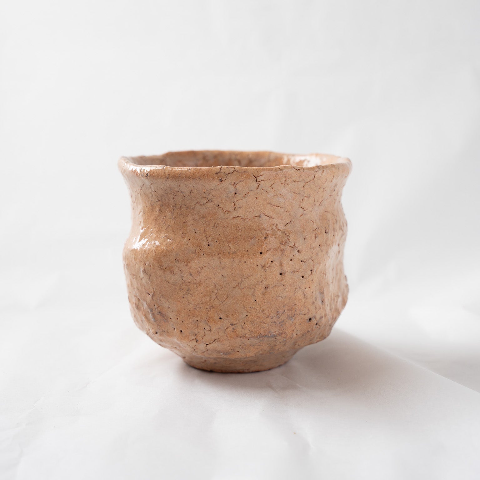 Alternate side profile of the loquat-glazed cup, emphasizing the fine grid of crackle lines and subtle asymmetric lineaments formed during firing.