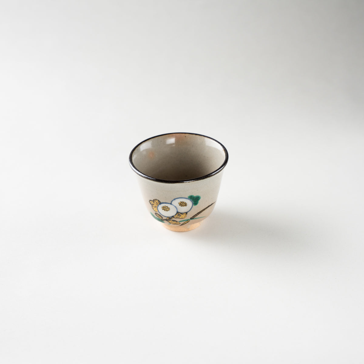 Turned perspective of the Kiku ceramic GUINOMI by Eiraku Zengoro XVI, highlighting the dark iron rim and delicate white chrysanthemum blossoms.