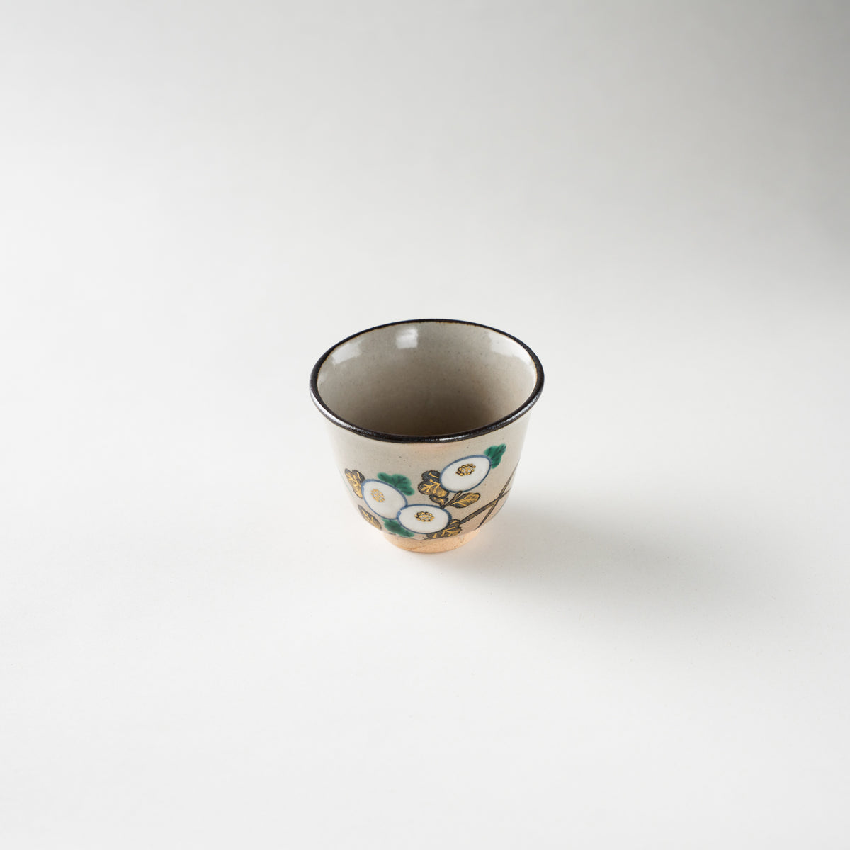 High-angle view of the Kiku chrysanthemum GUINOMI sake cup by Eiraku Zengoro XVI, featuring a warm ash-grey glaze and gold-accented floral motifs.