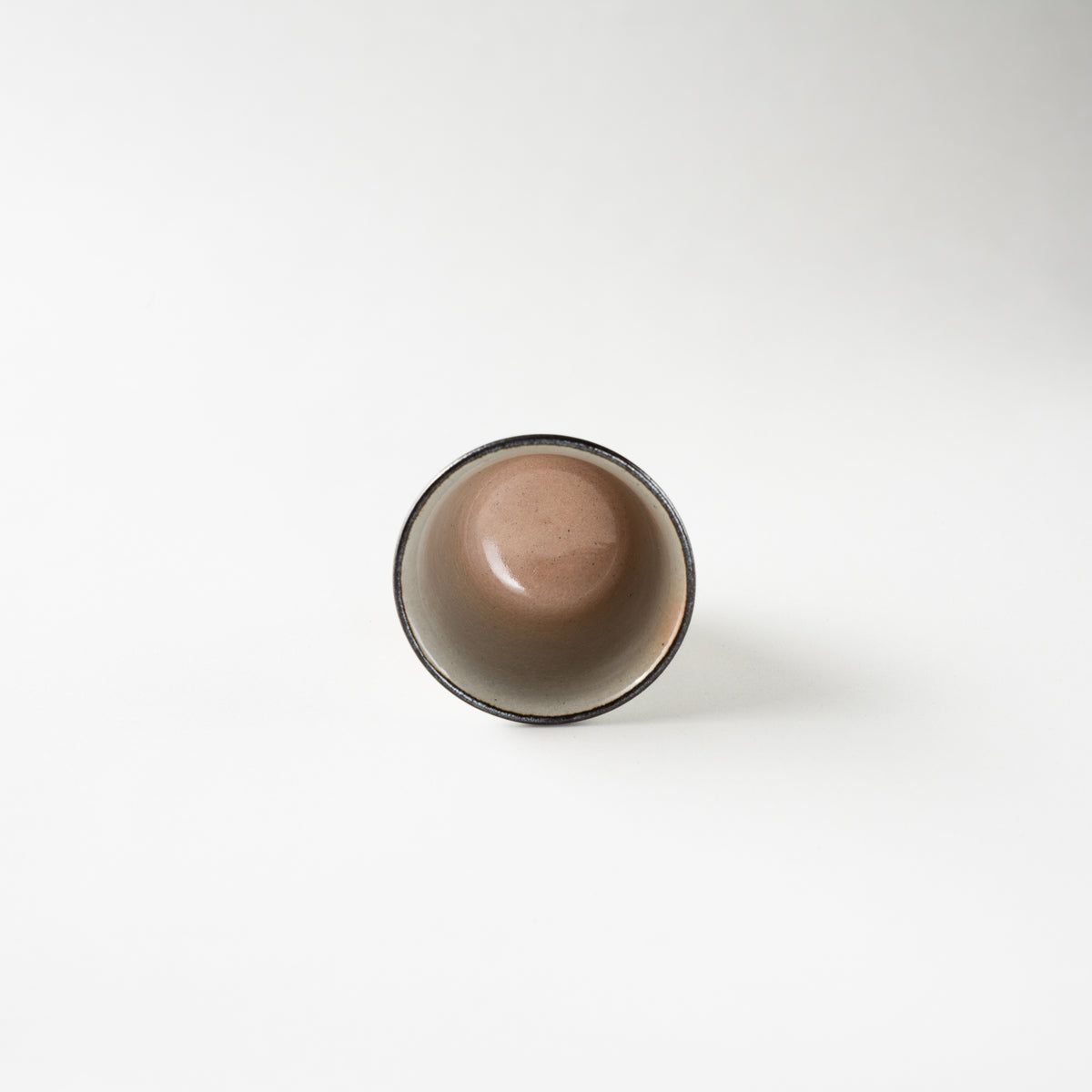 Top-down interior view of the ceramic GUINOMI by Eiraku Zengoro XVI, showing the smooth, warm grey glazed basin and precise dark rim.