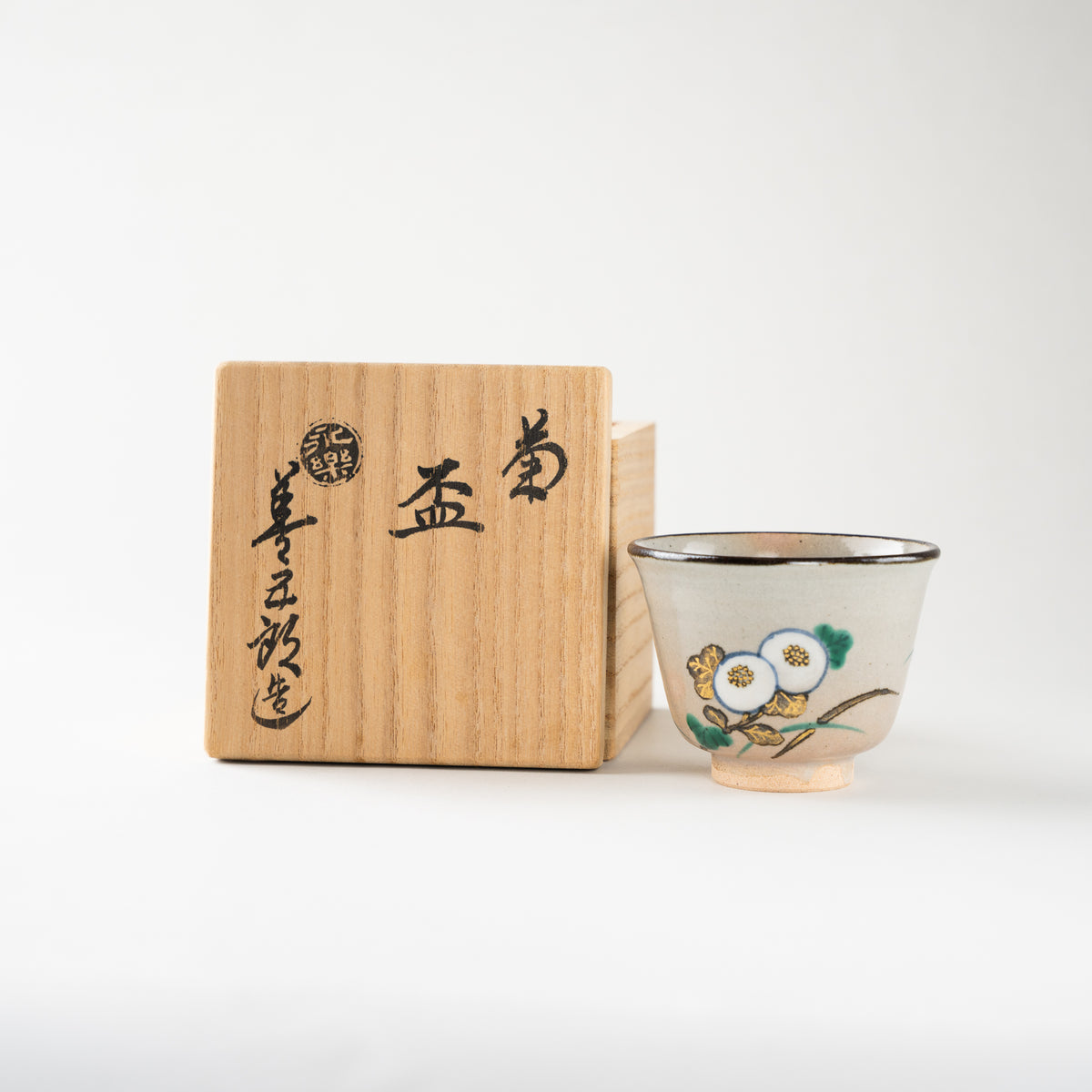 The Kiku GUINOMI sake cup by Eiraku Zengoro XVI displayed alongside its signed wooden tomobako box, highlighting its collectible gallery presence.