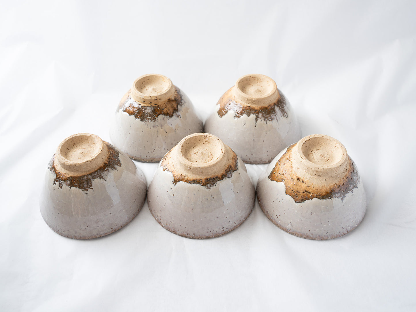 Close-up of the inverted Hagiyaki cups, detailing the artisanal glaze runs and rough tactile textures around the circular foot rings.