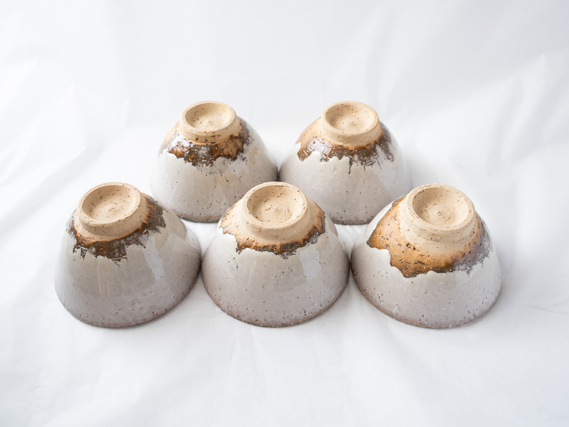 Close-up of the inverted Hagiyaki cups, detailing the artisanal glaze runs and rough tactile textures around the circular foot rings.