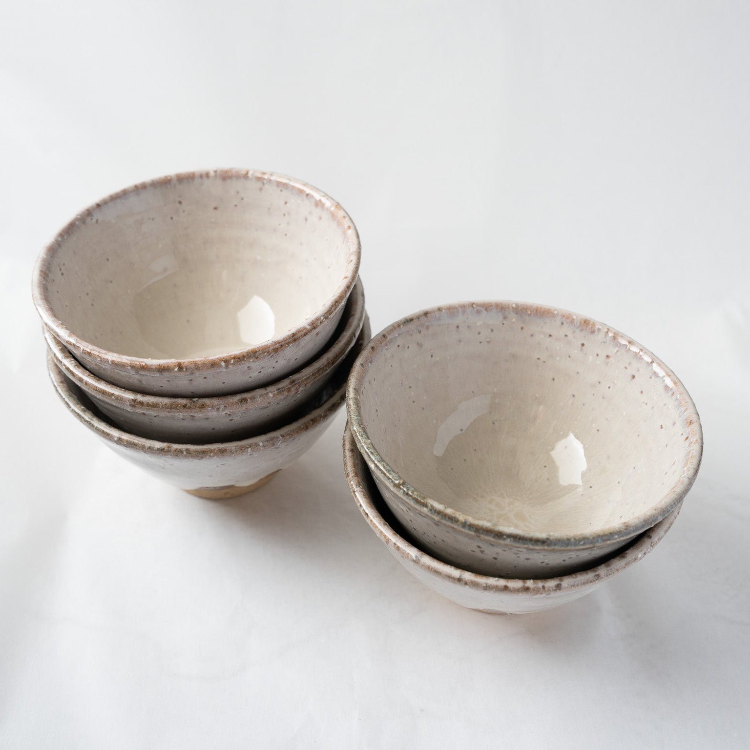 A vertical stack of five Hagiyaki tea cups placed next to their traditional paulownia wooden box with handwritten Japanese calligraphy and a red artist stamp.
