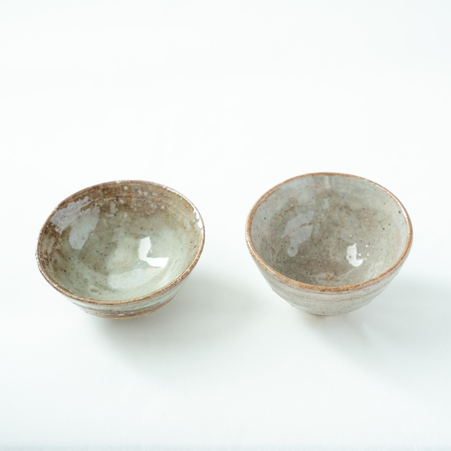 Top-down angled view looking into the glossy, pale blue-gray interior of the two cups, revealing the elegant depth and smooth glaze finish.