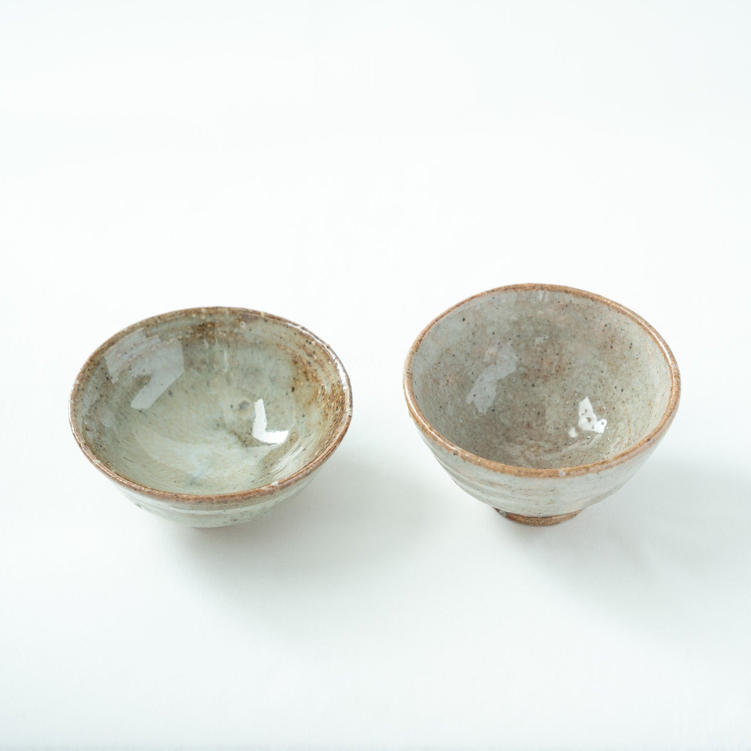 Close-up top view looking inside the bowls, emphasizing the fine crackles and calm pool of glaze at the bottom of the vessels.