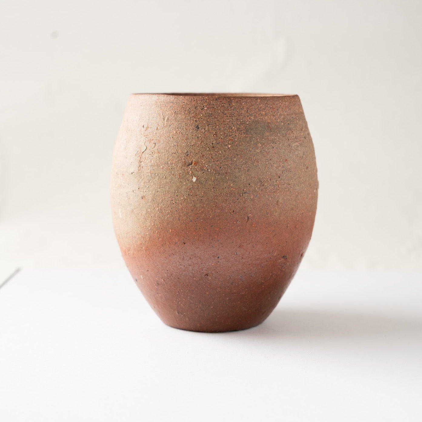 Side profile showing the fine speckles and rustic texture of the wood-fired clay under soft natural lighting.