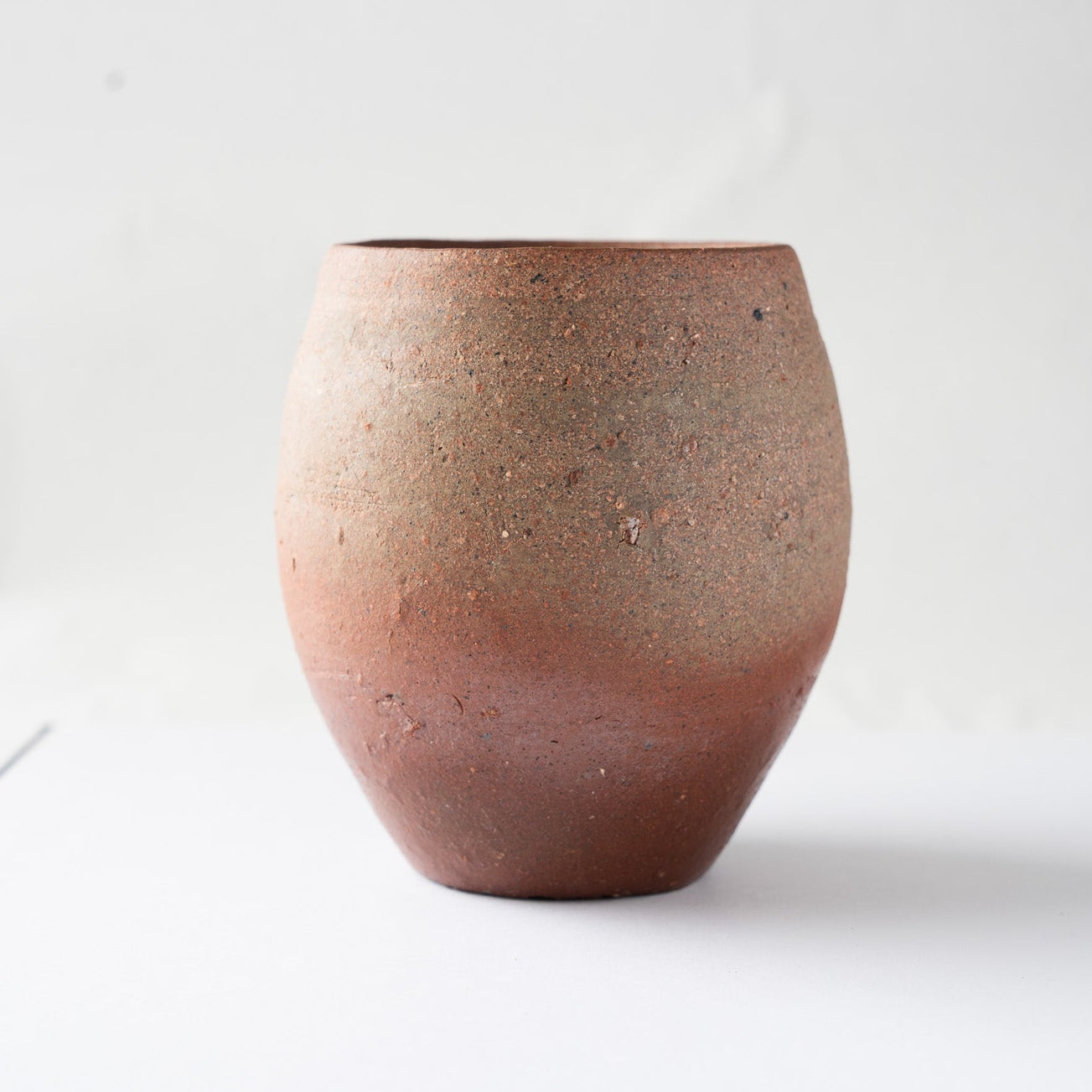 Profile view focusing on the rich dark-brown tones and the slightly irregular, hand-formed rim of the unglazed vessel.