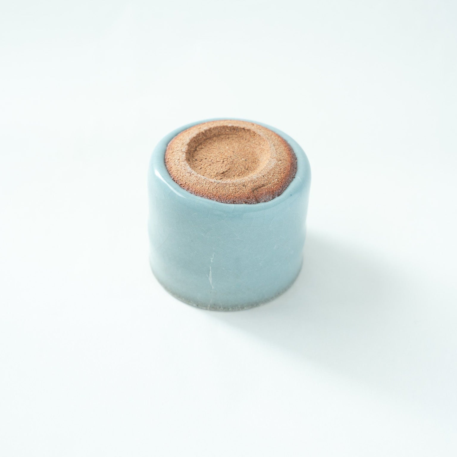 Detailed view of the unglazed foot, showcasing the earthy, organic texture of the clay and the clean boundary where the celadon glaze ends.