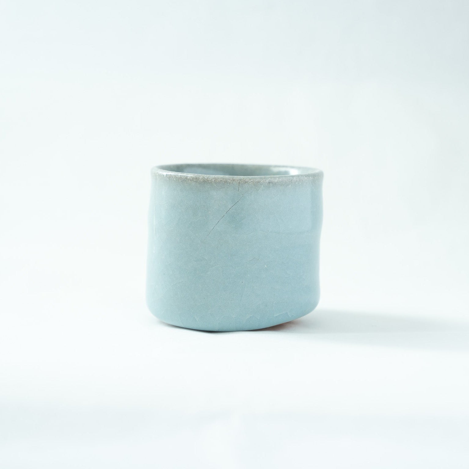 Detailed side view of the vessel, capturing a distinctive diagonal crackle line running through the translucent blue-green glaze.
