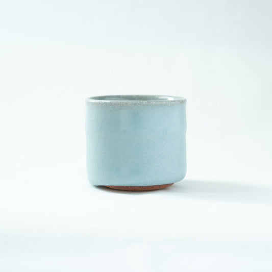 Side view of the celadon sake cup, highlighting the gentle irregularities of the hand-formed silhouette and the glossy, serene glazed surface.