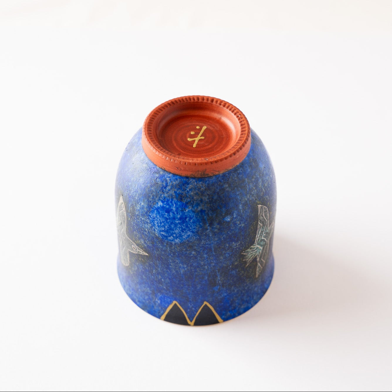 Unglazed reddish terracotta foot of the inverted blue YUNOMI cup, showing the artist’s signature symbol hand-painted in gold.