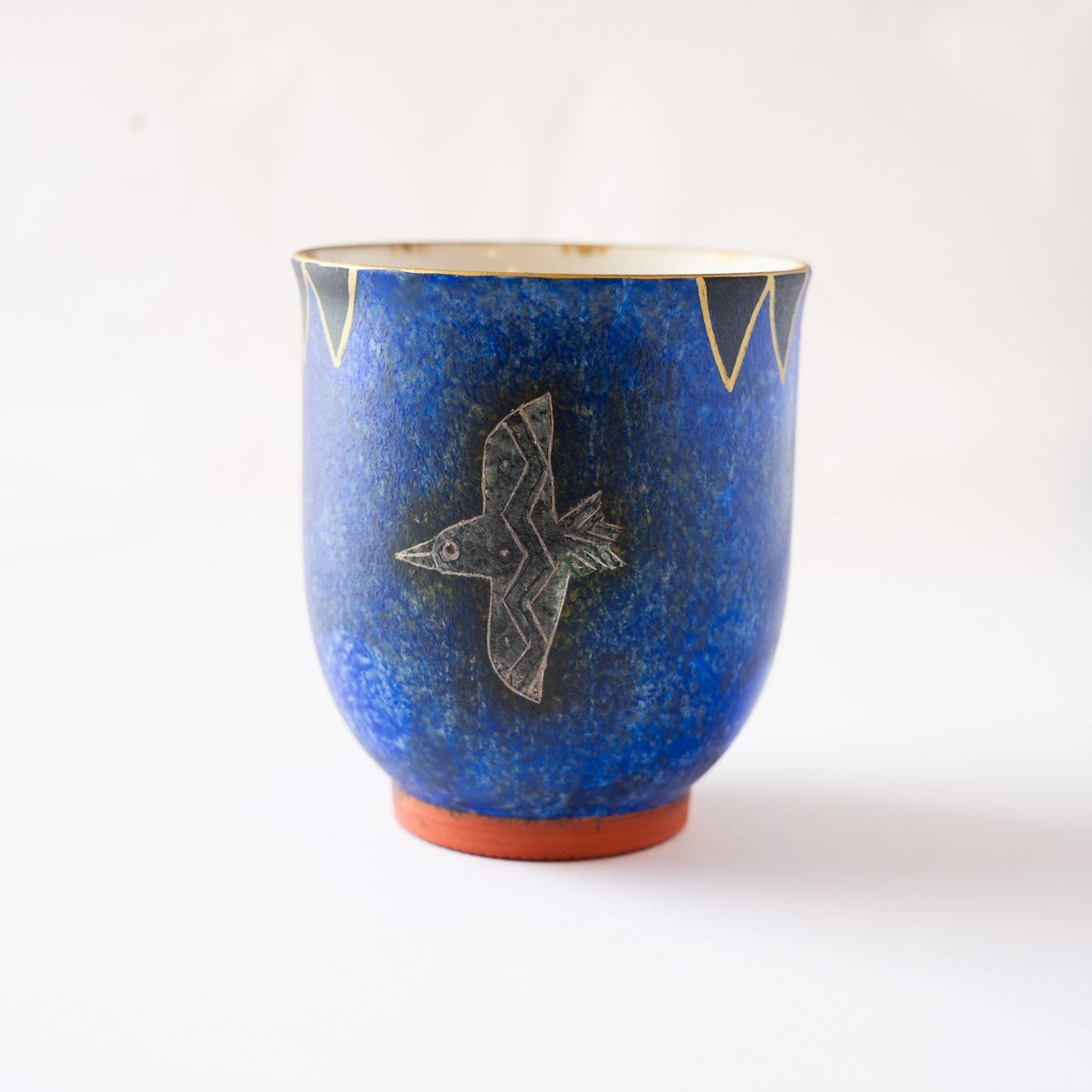 Front profile view of the blue YUNOMI cup showcasing the full form of the engraved flying bird and the sharp geometric border along the upper rim.