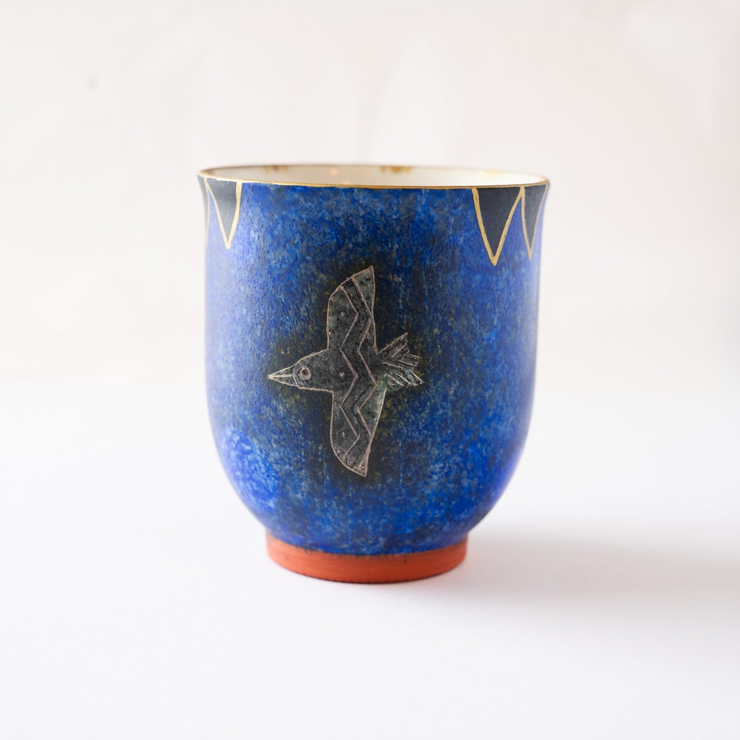 Front profile view of the blue YUNOMI cup showcasing the full form of the engraved flying bird and the sharp geometric border along the upper rim.