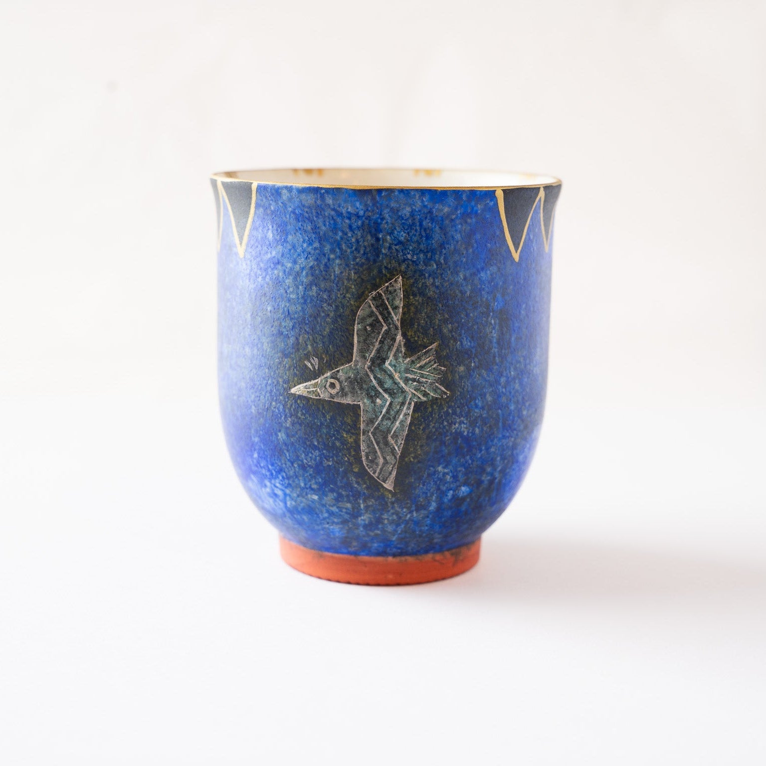 Profile view capturing the tactile depth of the deep blue background glaze and the structural contrast of the unglazed circular foot ring.