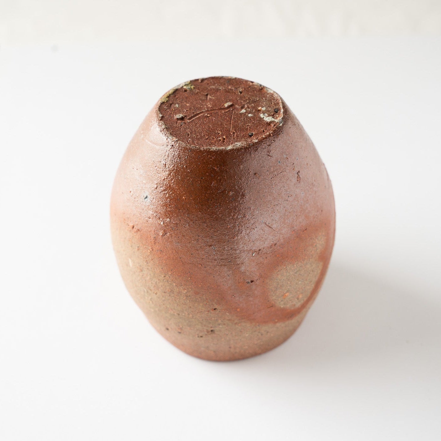 Inverted look at the YUNOMI cup displaying the flat unglazed base with a subtle incised artist signature mark and firing traces.