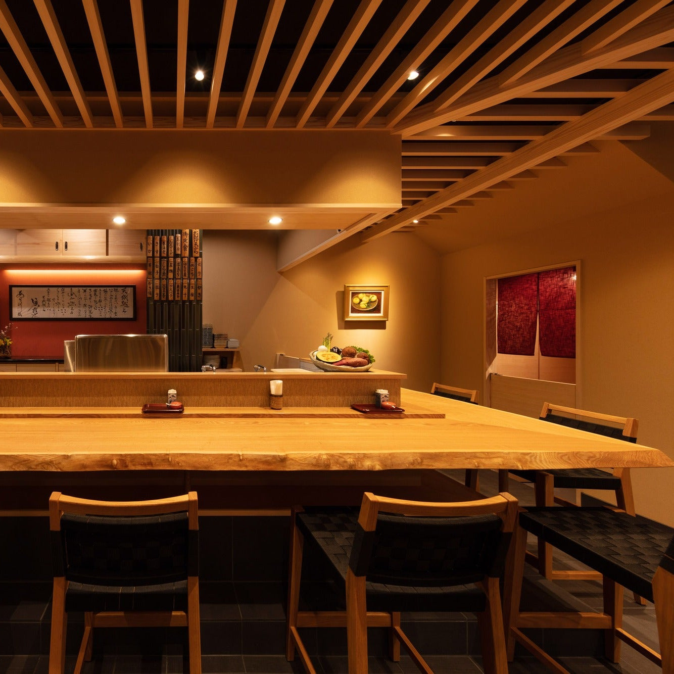 Chef's counter facing an open kitchen with a calligraphy curtain and a red accent wall.
