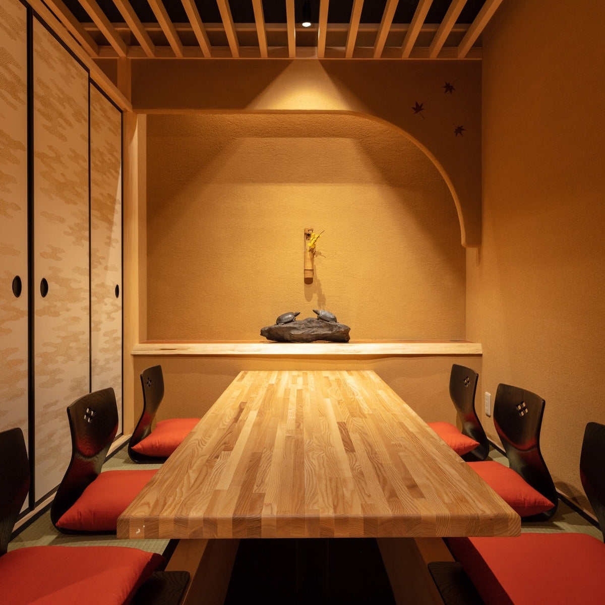 Symmetrical private room with red floor cushions and an arched niche, an intimate izakaya space in Tokyo.