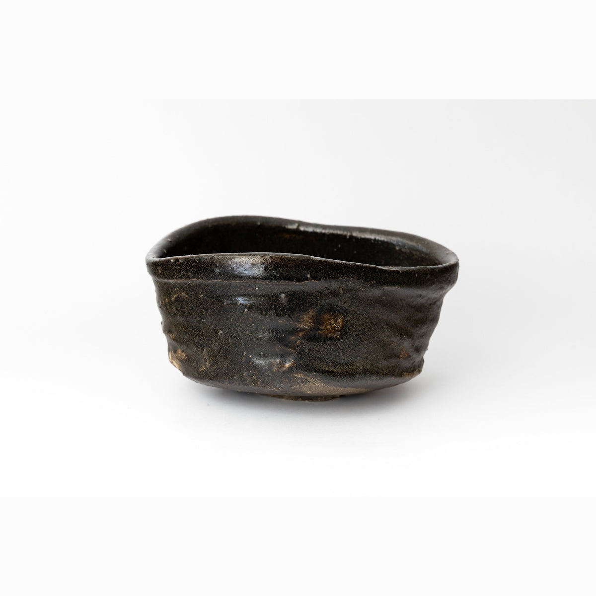 Front view of the wide oval hikidashi-black tea bowl on a white ground, showing the horizontal throwing rings and the rust breaks in the dark glaze.