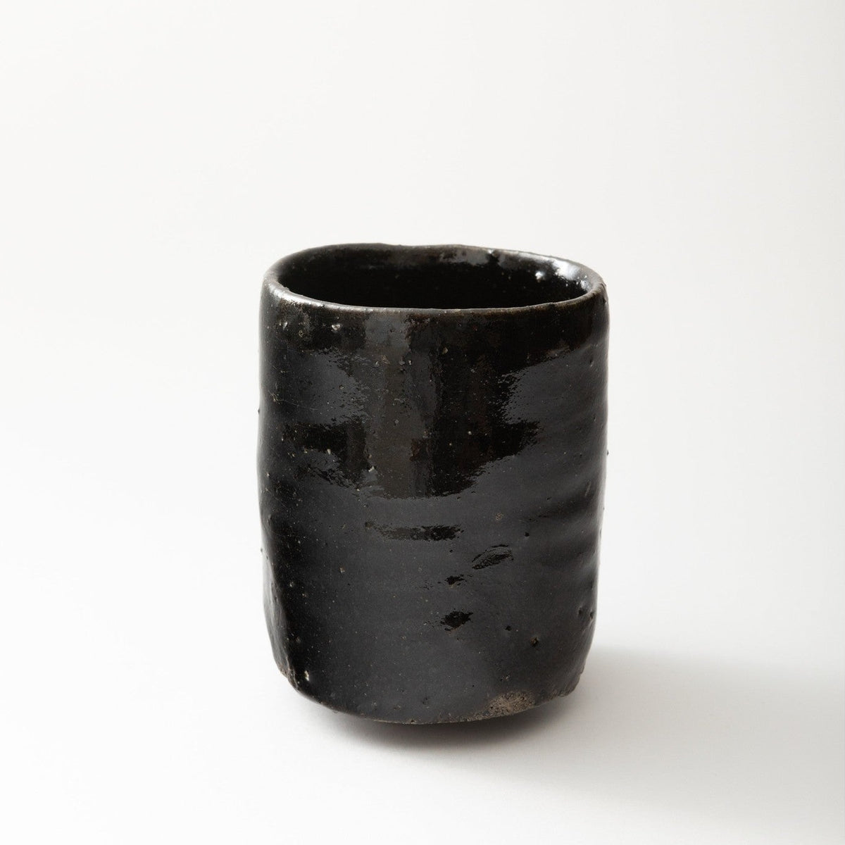 Side view of the cup, slightly lit from above, showing the horizontal throwing lines on the black surface.