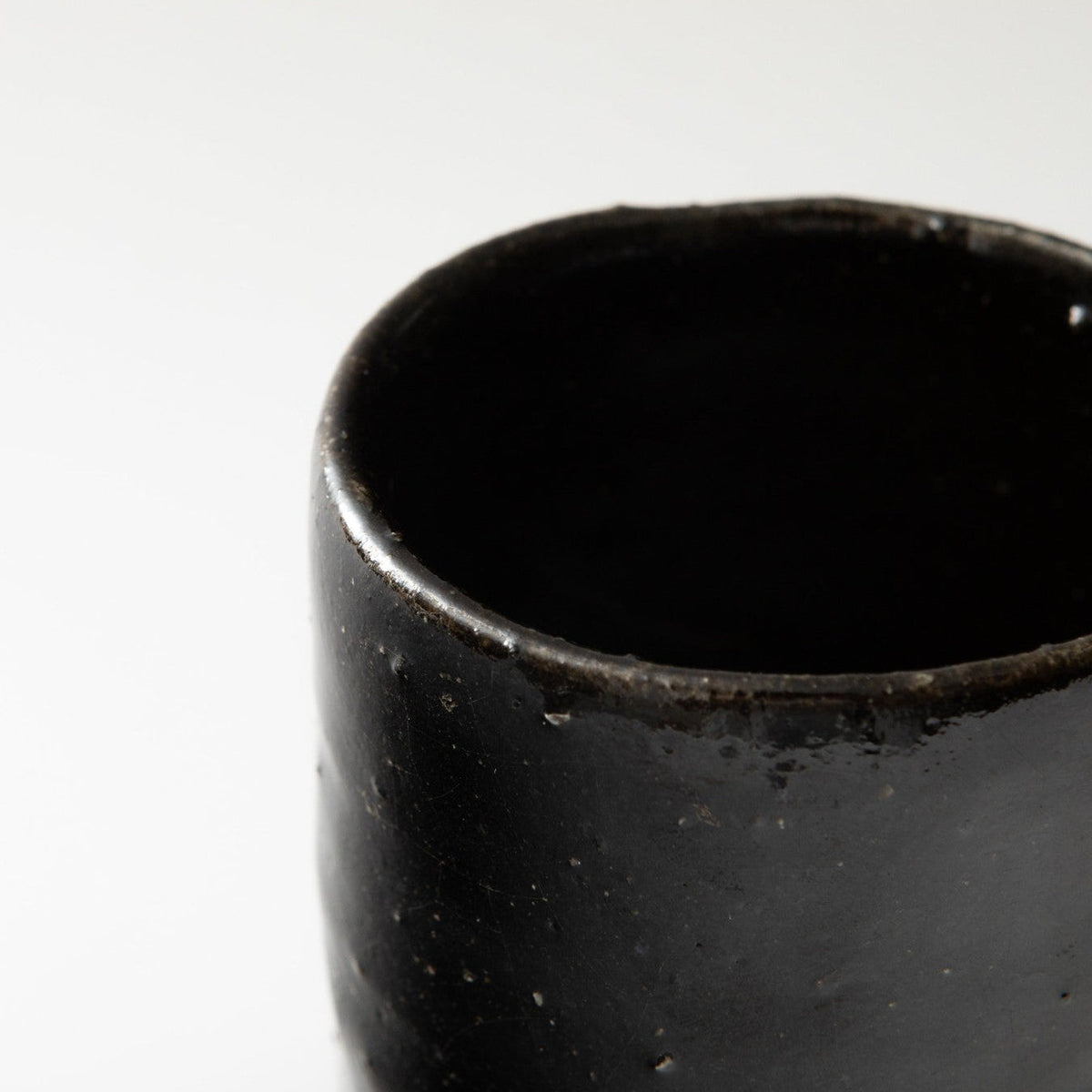 Close view of the rim and interior, the black glaze glossy and dark with a soft reflection inside.