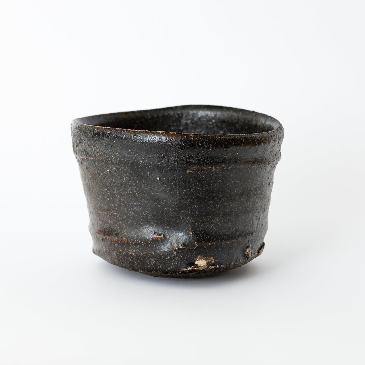 Front view of an Oribe Chawan tea bowl by Kai Tsujimura, with a low balanced form and a deep dark surface.