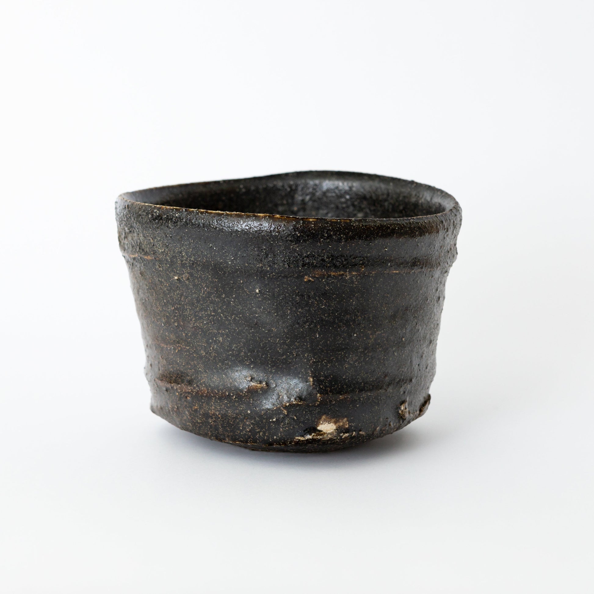 Front view of an Oribe Chawan tea bowl by Kai Tsujimura, with a low balanced form and a deep dark surface.
