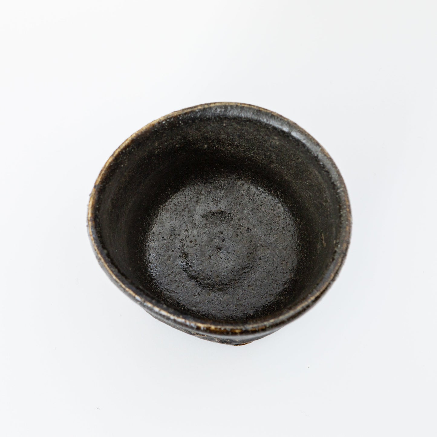 Top view of an Oribe Chawan tea bowl by Kai Tsujimura, showing a deep dark interior and a softly irregular rim.