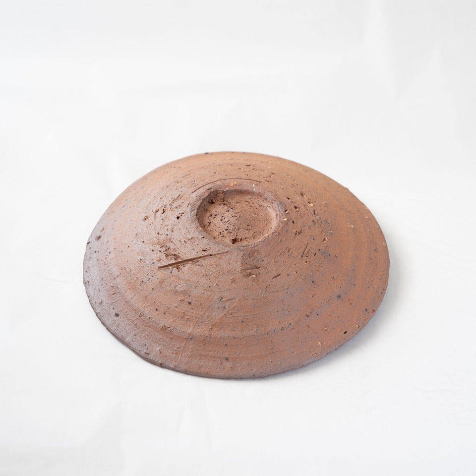 Reverse view of a dark brown earthy yakishime plate by Kai Tsujimura, highlighting the rough carved foot and organic tool marks in the raw clay.