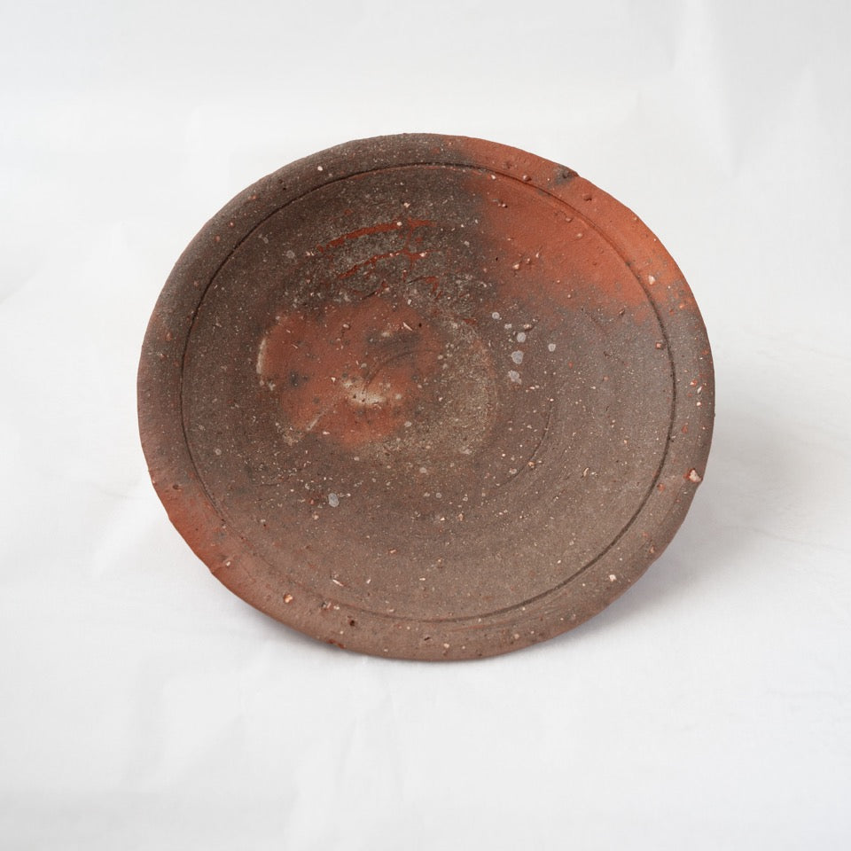 Front view of a dark yakishime plate by Kai Tsujimura, showcasing an orange flame transition, natural textures, and a slightly irregular rim.