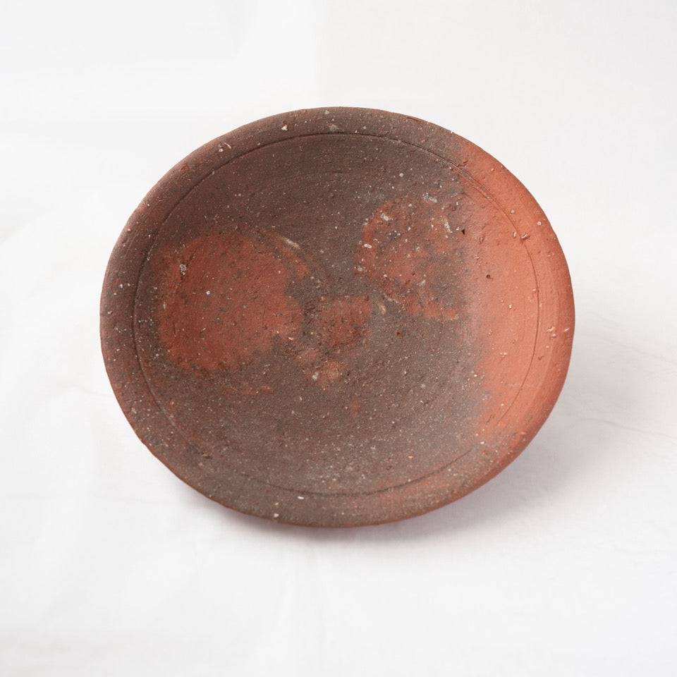 Front view of a dark grey yakishime plate by Kai Tsujimura, showing twin reddish circular fire marks formed naturally during the kiln firing.