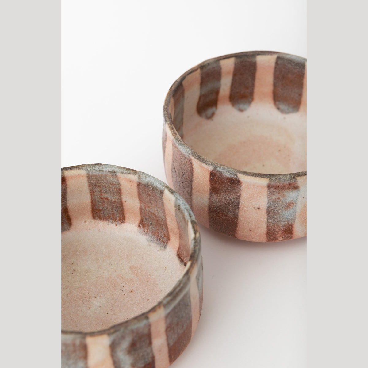 Close view from above of a dish's rim and interior, pinholes and orange-peel texture in the white glaze.