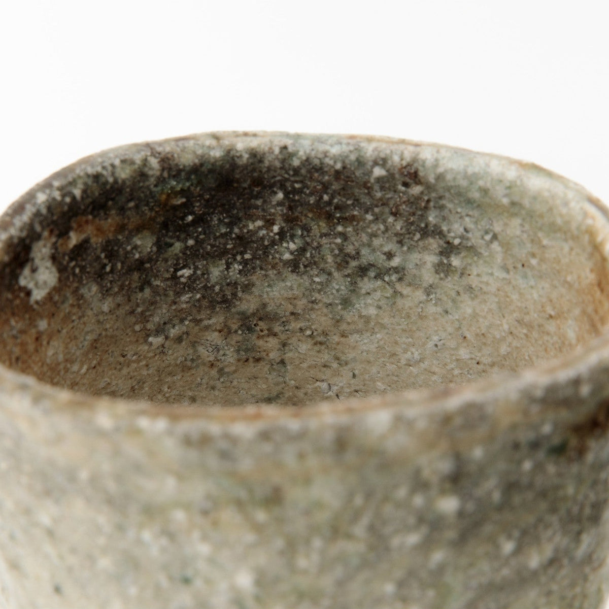 Close view of the rim and upper wall, the rough ash coat and speckled surface in even light.