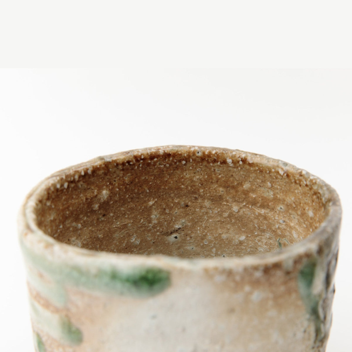 Detail of the bowl's mouth showing green ash melt at the rim and the warm interior beyond.