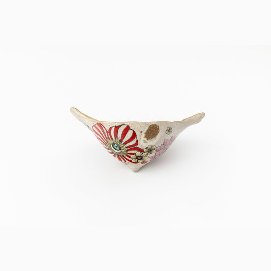 L'objet vu de l'autre côté, montrant une figure en robe rayée rouge et blanc peinte à l'émail de surglaçure.