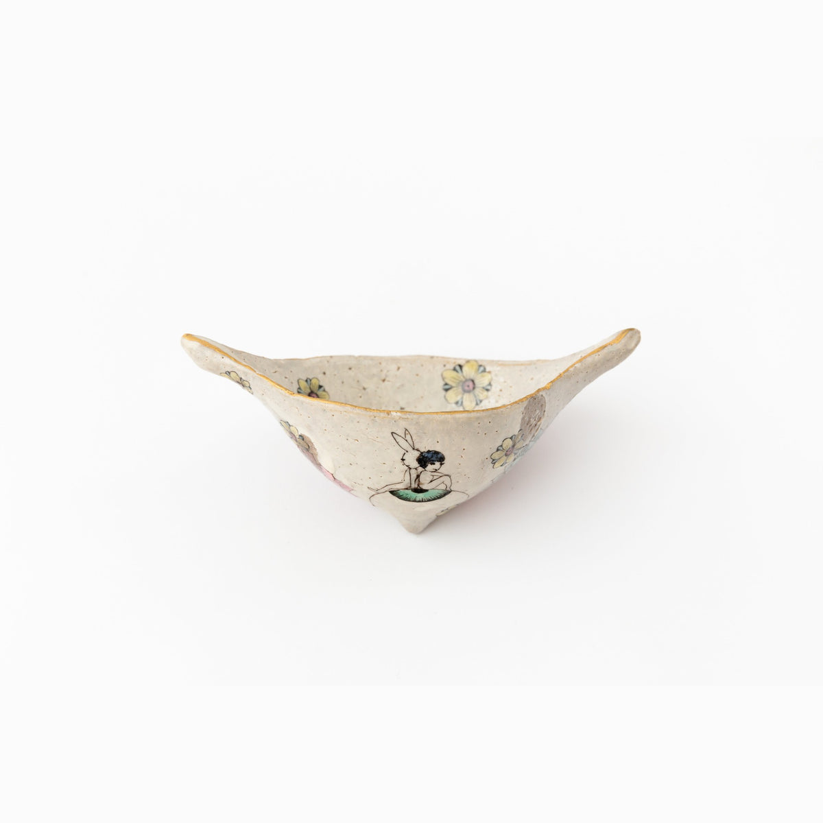 Side view of the object, the thin pale clay and delicate enamel decoration in even light.