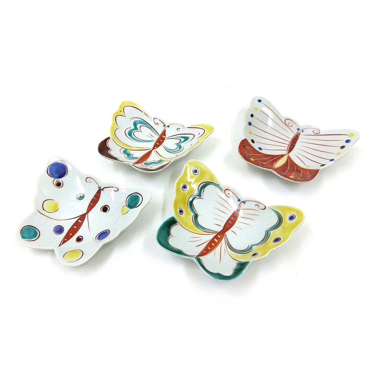 Six petites assiettes en forme de papillon disposées sur fond blanc, en jaune, blanc et bleu, rehaussées d'émaux rouges, verts et noirs ; vendues par ensemble de six.